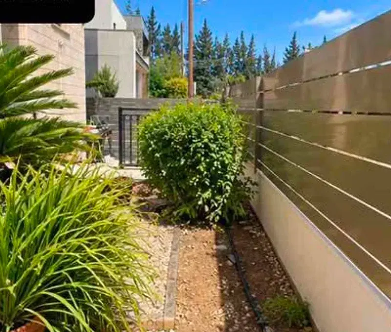 Clean planted garden bed with gravel and a boundary fence in Limassol